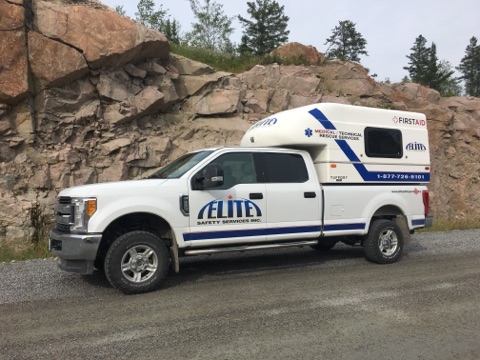 Turnaround Safety - Worker using a laptop; factory in background.